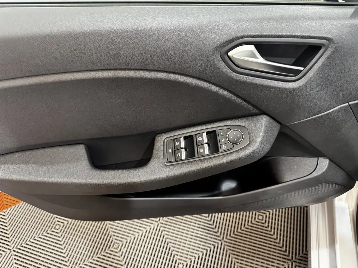 Vue rapprochée de la porte côté conducteur de la Renault Clio Business TCe 100 2020 avec commandes de vitres électriques et poignée grise.