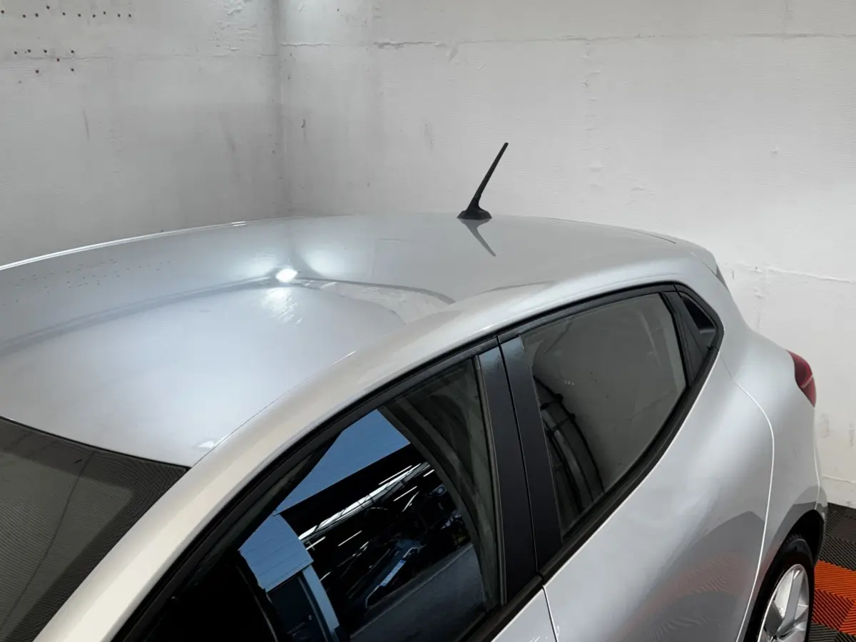 Vue 3/4 arrière droite d'une Renault Clio Business gris clair avec vitres teintées et antenne de toit noire.
