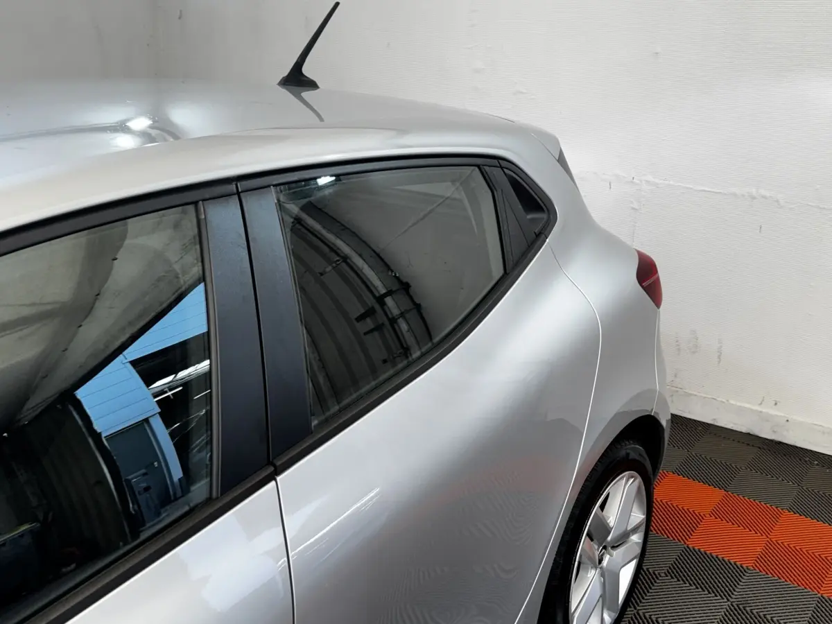 Vue côté gauche arrière d'une Renault Clio Business gris clair, avec vitres teintées et jantes alliage visibles.