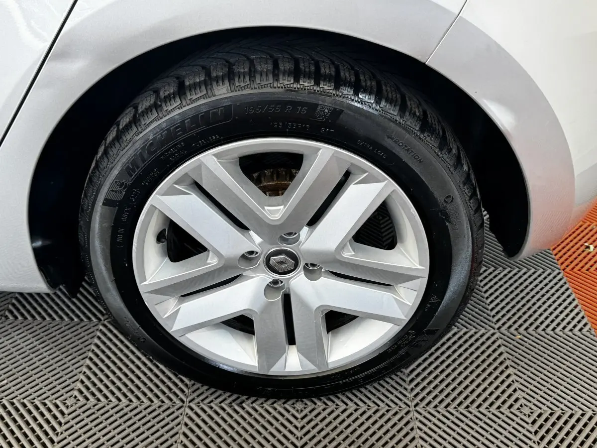 Gros plan sur la roue avant droite gris clair d'une Renault Clio Business TCe 100 avec jante en alliage et logo Renault central.