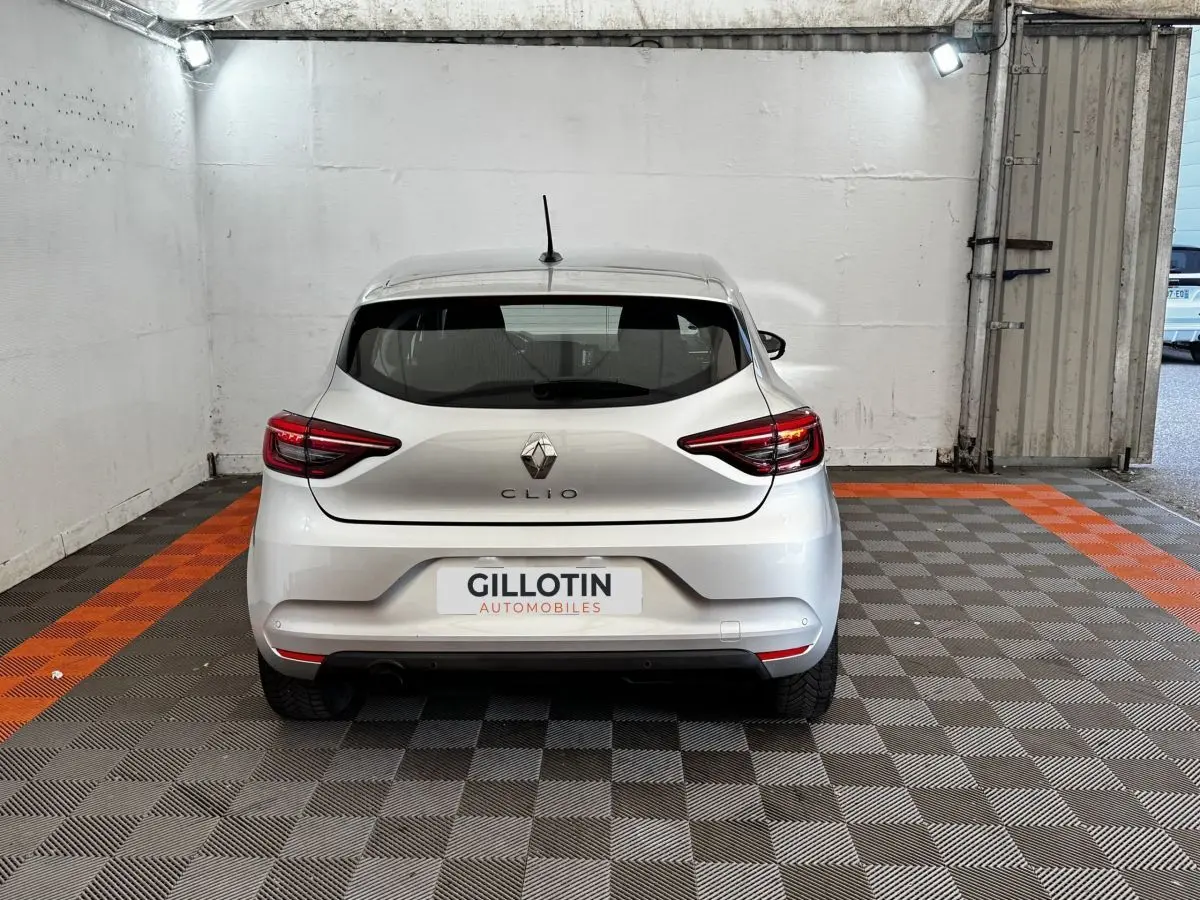Vue arrière d'une Renault Clio gris clair 2020 garée en intérieur avec feux arrière LED allumés.