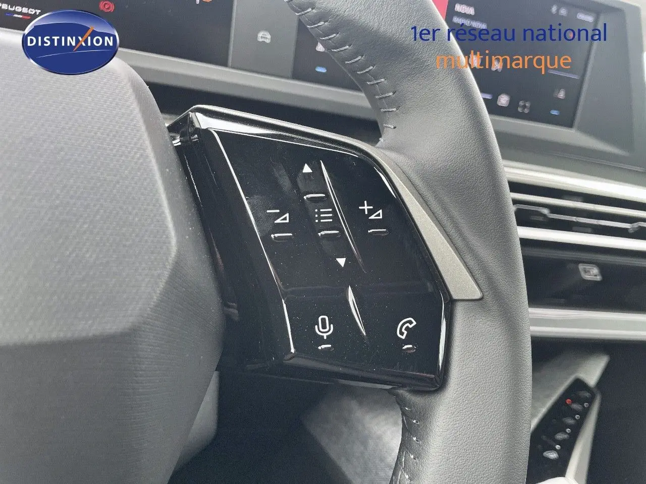 Gros plan sur les commandes gauche du volant cuir noir du Peugeot 3008 Hybrid 2025 avec écran tactile en arrière-plan.