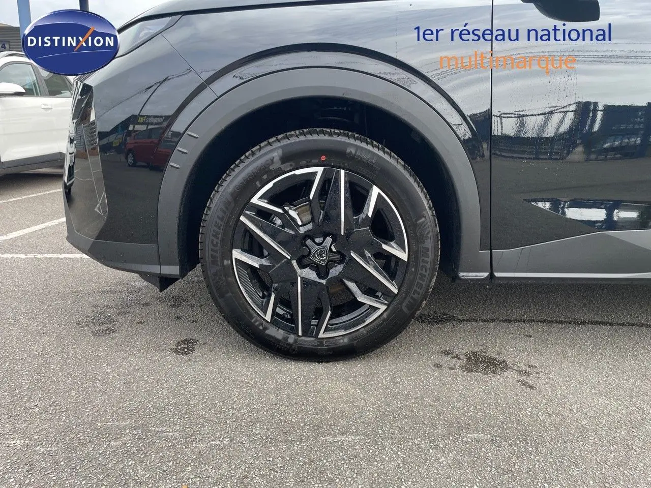Gros plan sur la roue avant gauche du Peugeot 3008 noir perle métal, soulignant la jante alliage bicolore moderne.