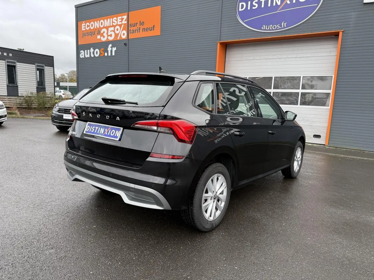 Vue 3/4 arrière droite d'un Skoda Kamiq noir Magic nacré avec feux arrière LED et jantes argentées sur parking.