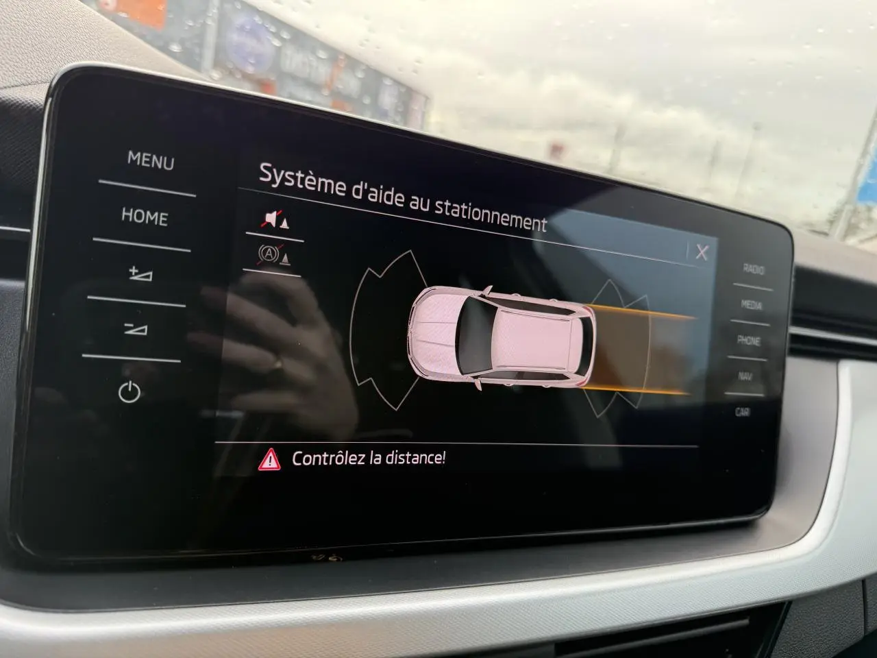 Écran tactile intérieur du Skoda Kamiq 2023 montrant l'aide au stationnement avec alertes de distance.