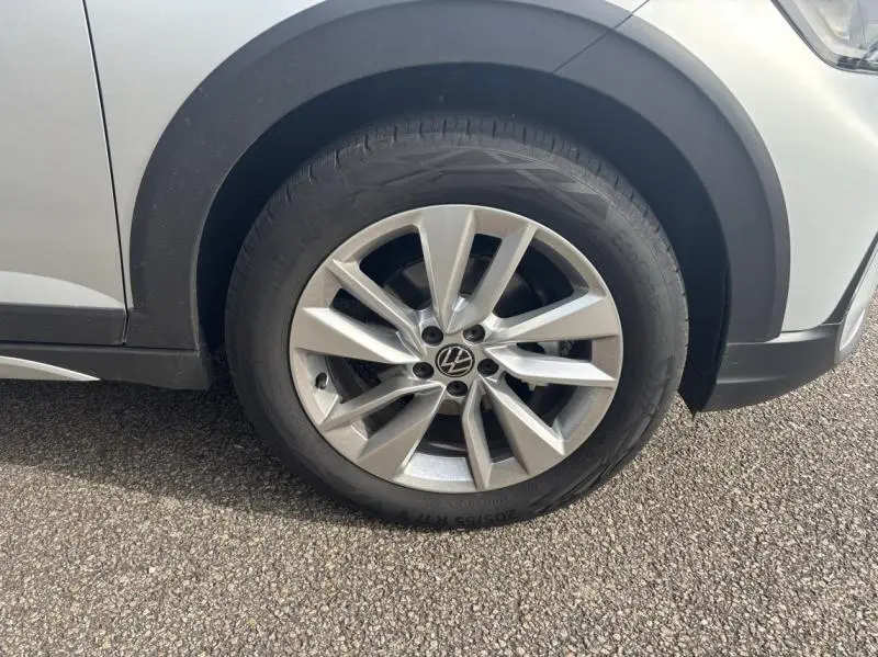 Gros plan sur la roue avant gauche d'un Volkswagen Taigo 2025 en Reflet d'Argent métallisé avec jante alu à 5 branches doubles.