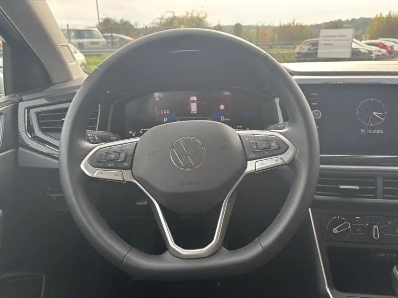 Vue intérieure centrée sur le volant cuir multifonction du Volkswagen Taigo 2025, avec tableau de bord digital en arrière-plan.