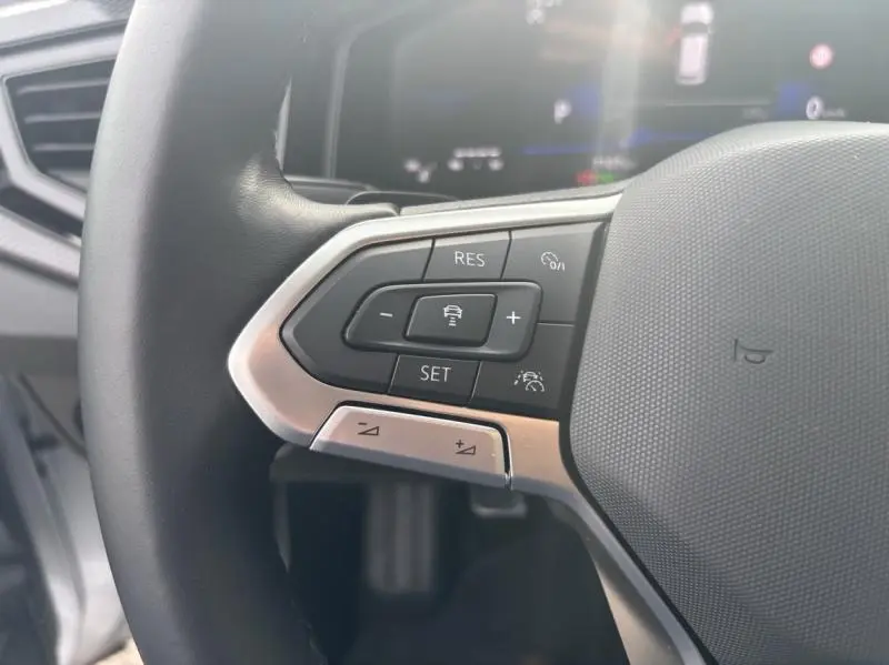 Gros plan sur les commandes multifonctions à gauche du volant cuir du Volkswagen Taigo 2025 en Reflet d'Argent.