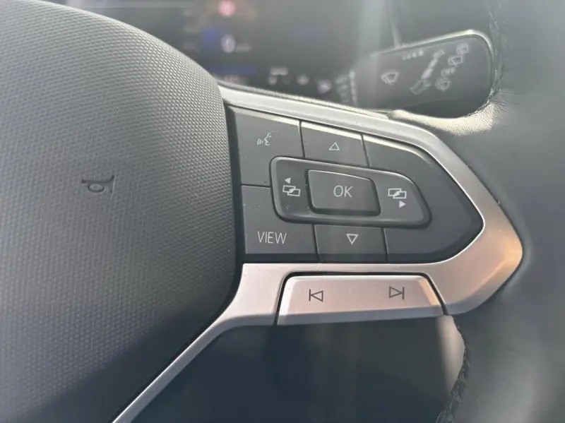 Gros plan sur les commandes multifonctions noires et argentées du volant cuir du Volkswagen Taigo 2025 côté gauche.