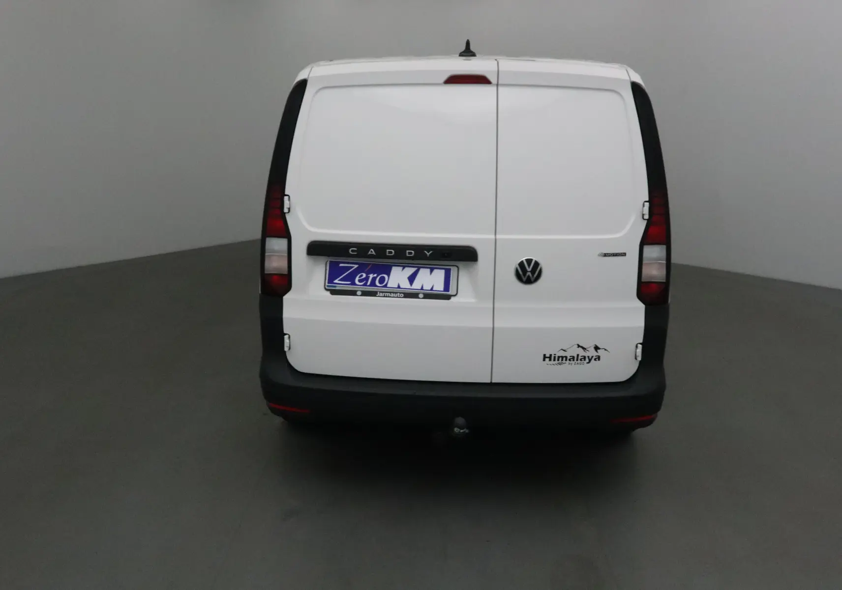 Vue arrière d'un Volkswagen Caddy Maxi blanc version Himalaya avec logo et attelage visibles.