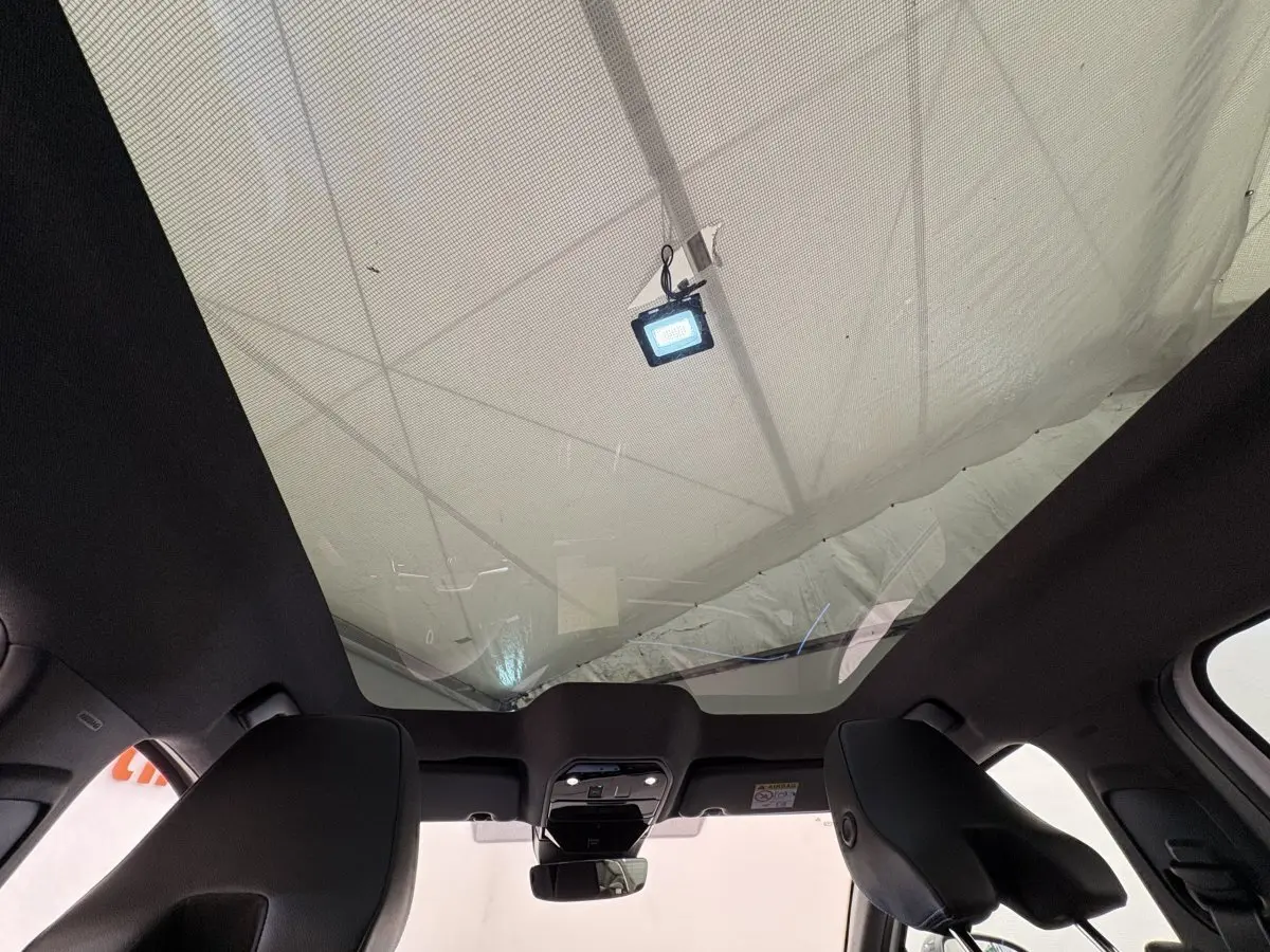 Vue intérieure du toit panoramique en verre du Renault Espace blanc, version Esprit Alpine 2025, avec plafonnier central et appuis-tête avant visibles.