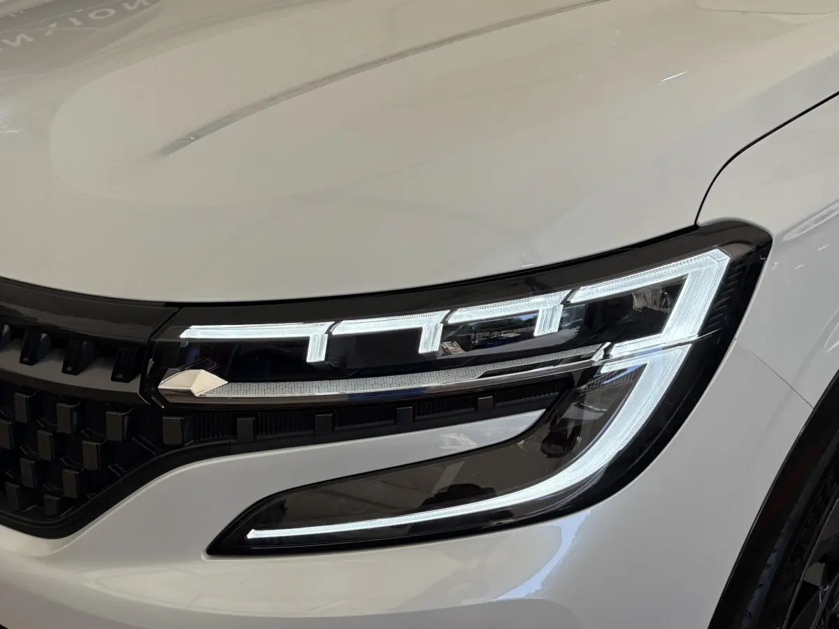 Gros plan sur le phare avant droit allumé du Renault Espace Esprit Alpine blanc, soulignant la signature lumineuse LED distinctive.