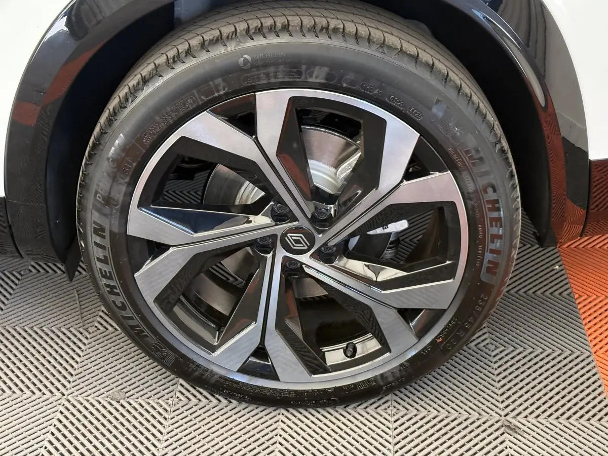 Gros plan sur la roue avant droite d’un Renault Espace blanc, avec jante alliage noire et argentée au design moderne.