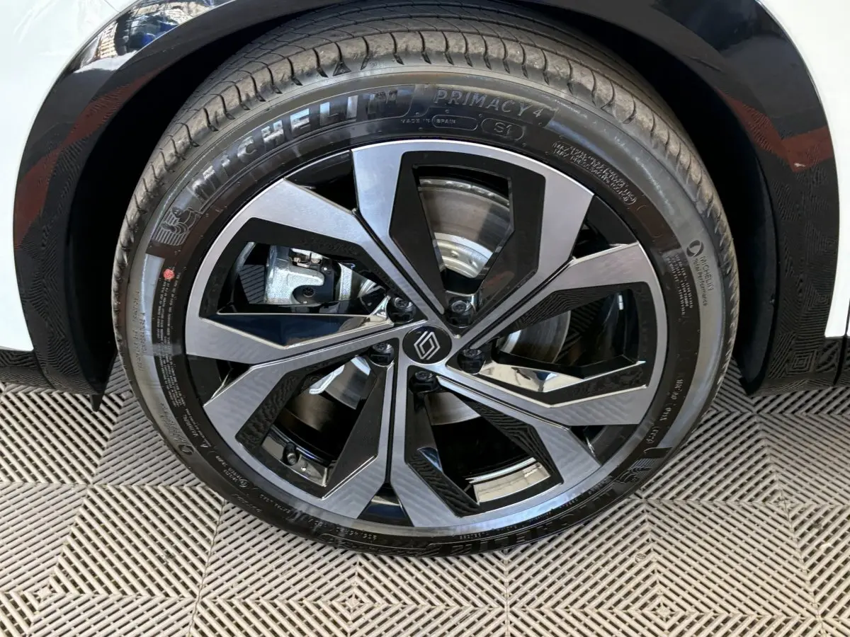 Gros plan sur la roue avant droite du Renault Espace blanc, jante alliage noire et argentée au design moderne.