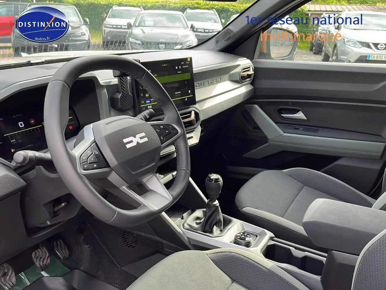 Intérieur du Dacia Duster 2025 essence, vue côté conducteur, volant multifonction et console centrale avec boîte manuelle.