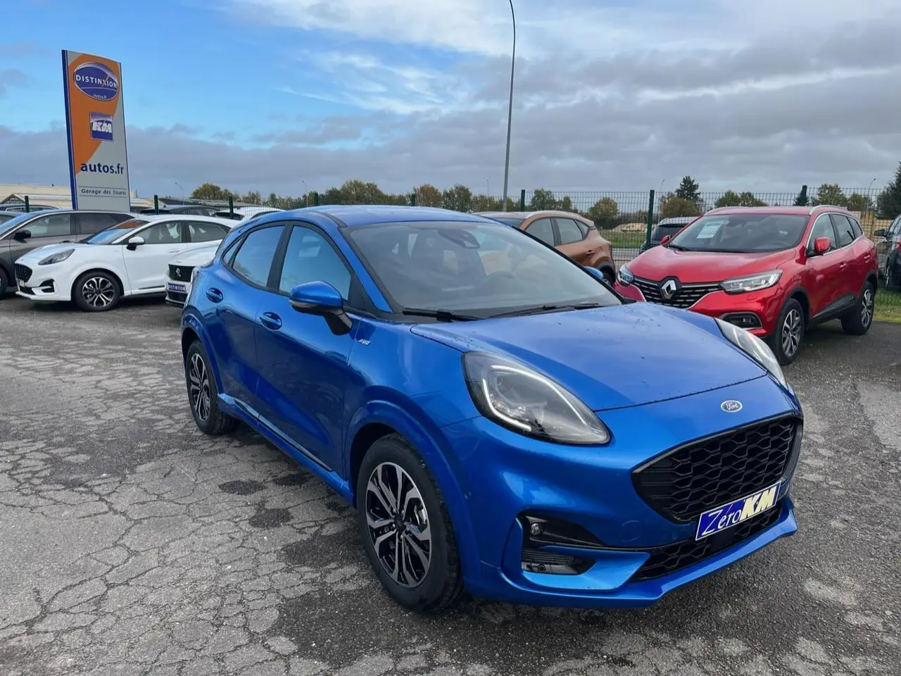 Ford Puma bleu métallisé en vue 3/4 avant droit, avec jantes alliage noires et calandre noire distinctive.