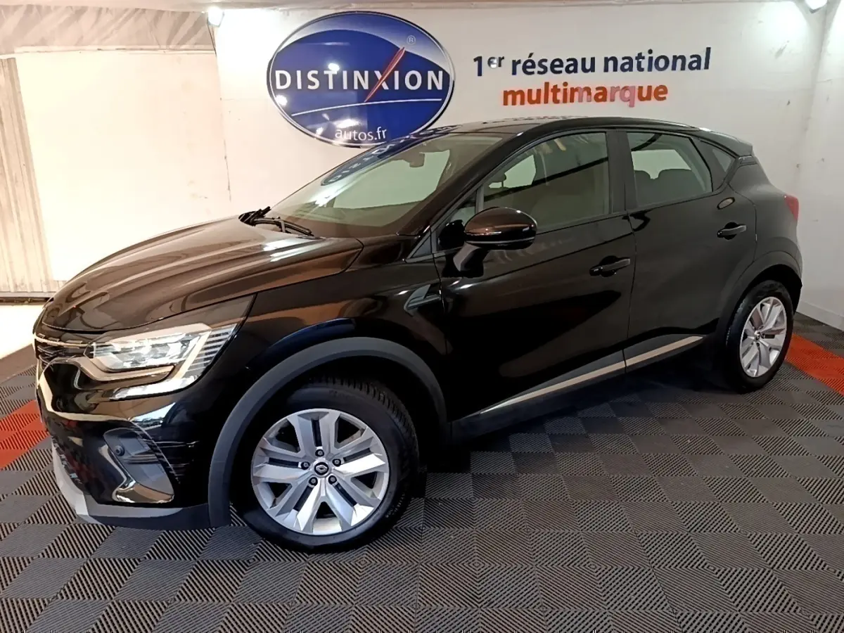 Renault Captur Business noir en 3/4 avant droit, avec jantes argentées et phares LED allumés en intérieur showroom.