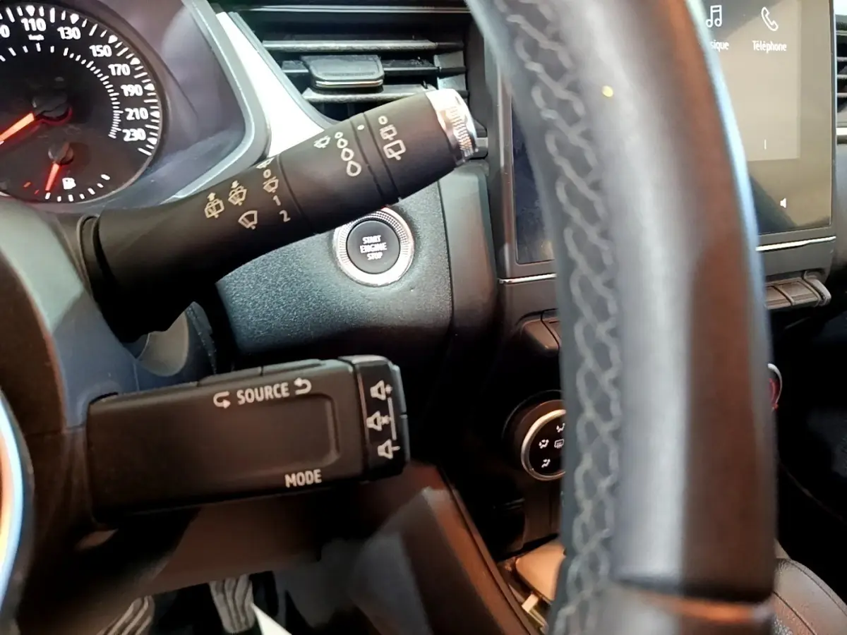 Gros plan intérieur sur le volant noir multifonctions et le tableau de bord avec bouton démarrage du Renault Captur Business 2021.