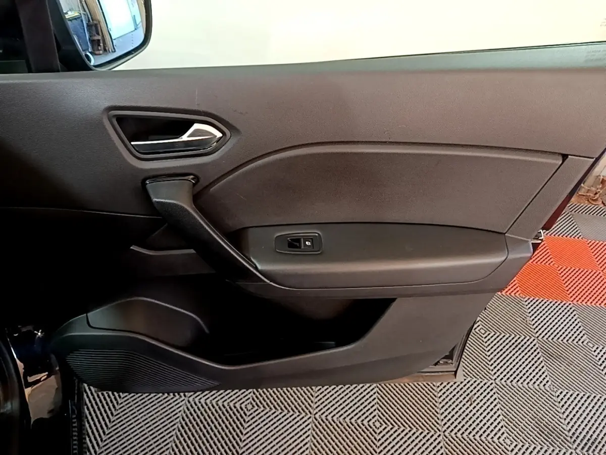 Vue intérieure côté gauche de la porte noire du Renault Captur 2021 avec poignée et commande de vitre électrique.