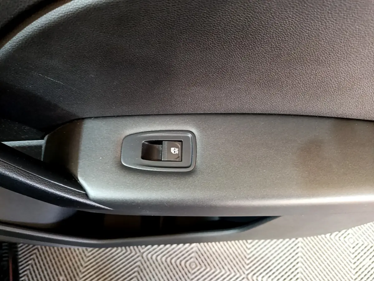 Gros plan sur le bouton de verrouillage des portes côté intérieur d'une Renault Captur Business noir, version 2021.