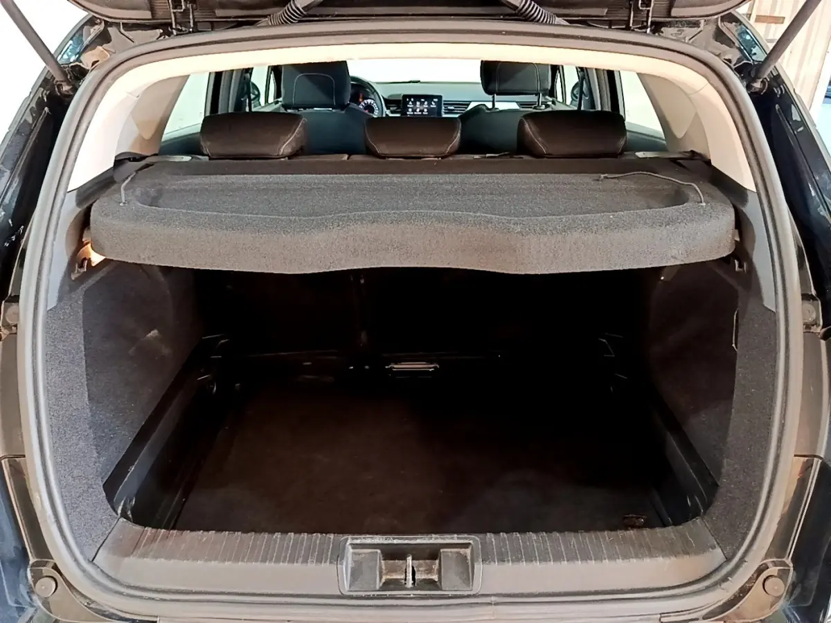 Coffre ouvert vu de l'arrière d'un Renault Captur Business noir, avec tablette cache-bagages et banquette arrière visible.