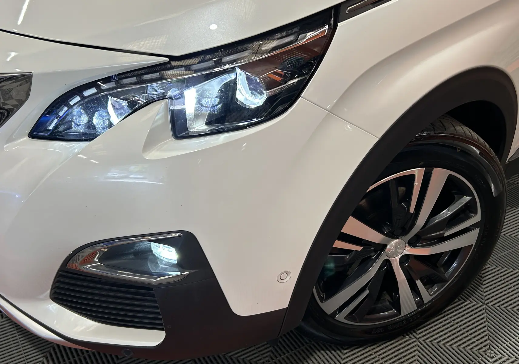 Gros plan sur l'avant droit blanc du Peugeot 3008 GT Line 2020, mettant en valeur le phare LED et la jante alliage.