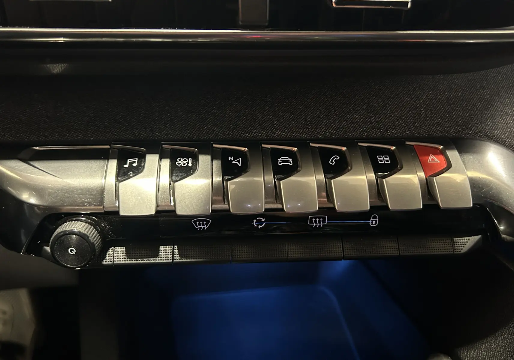 Gros plan sur la rangée de boutons chromés du tableau de bord du Peugeot 3008 GT Line 2020, éclairage intérieur bleu.