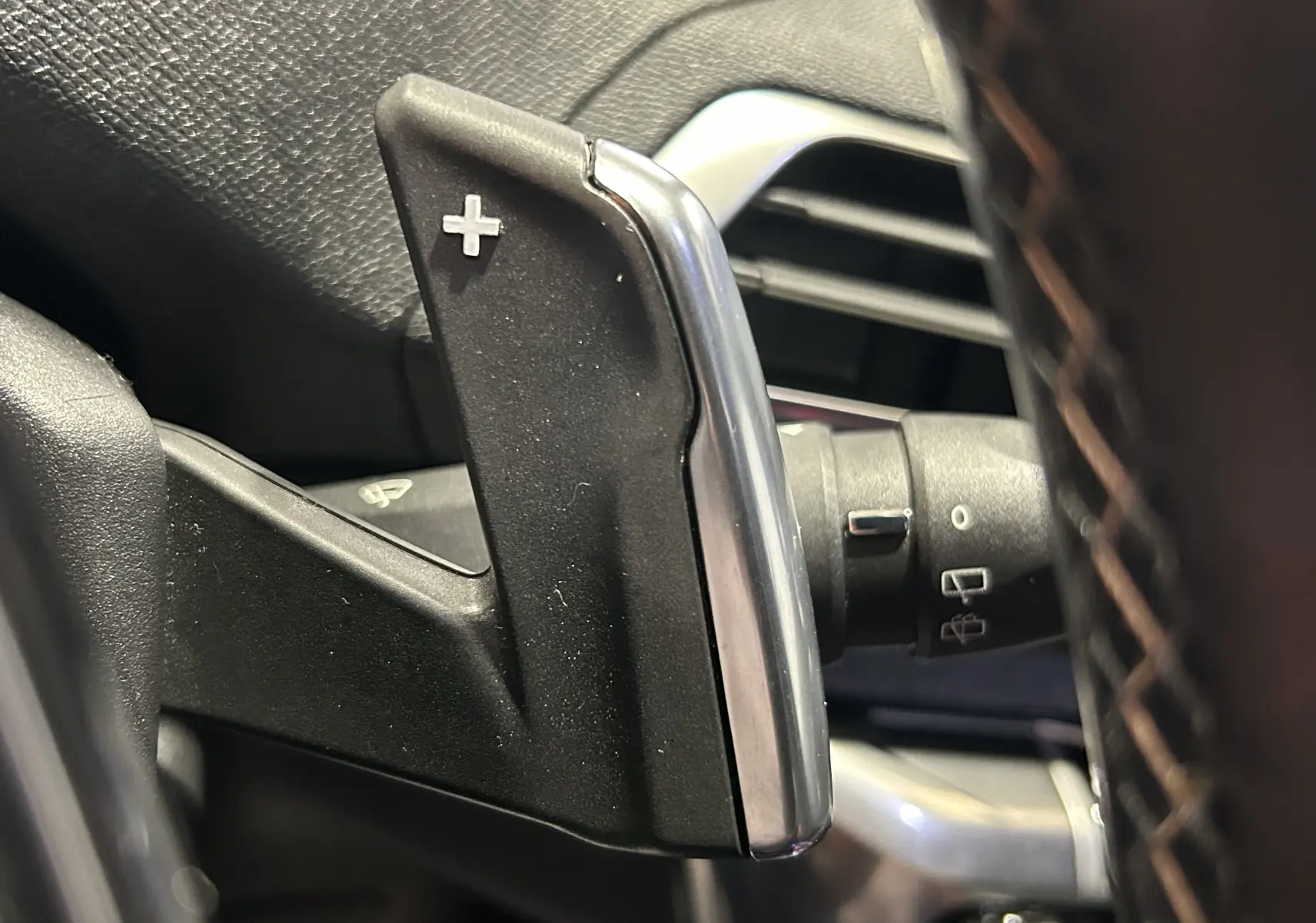 Gros plan sur la palette de changement de vitesse "+" côté droit du volant du Peugeot 3008 blanc, intérieur noir.