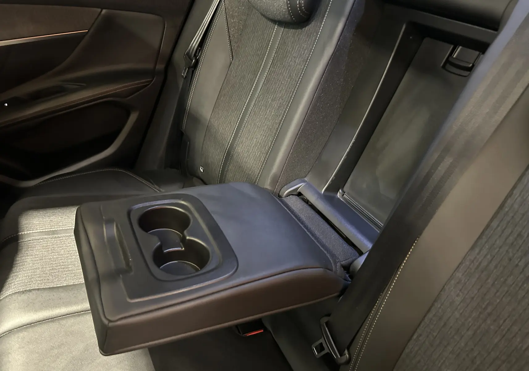 Vue intérieure côté droit des sièges arrière noirs du Peugeot 3008 GT Line 2020 avec accoudoir central et porte-gobelets déployés.