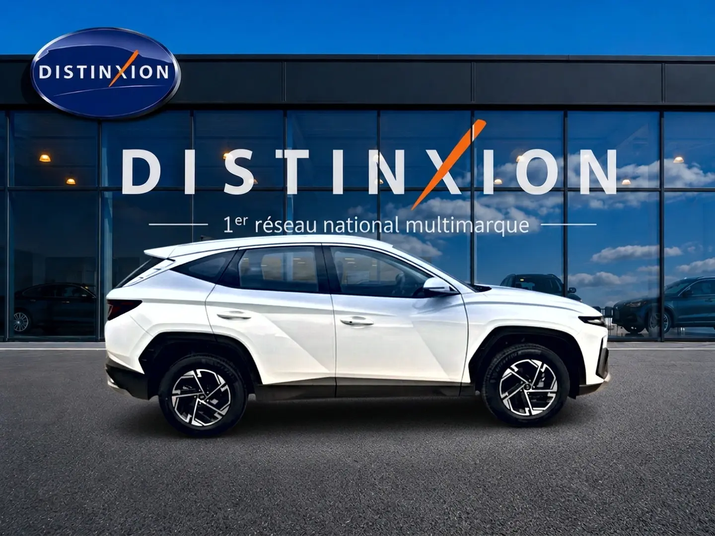 Vue de profil côté gauche d'un Hyundai Tucson blanc 2026 hybride, avec jantes alliage et lignes anguleuses marquées.