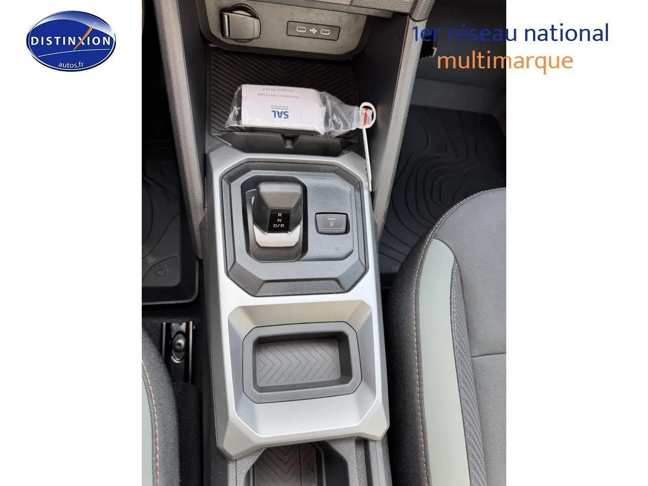Vue plongeante sur la console centrale du Dacia Duster 2025, avec levier de vitesses et accoudoir entre sièges noirs.