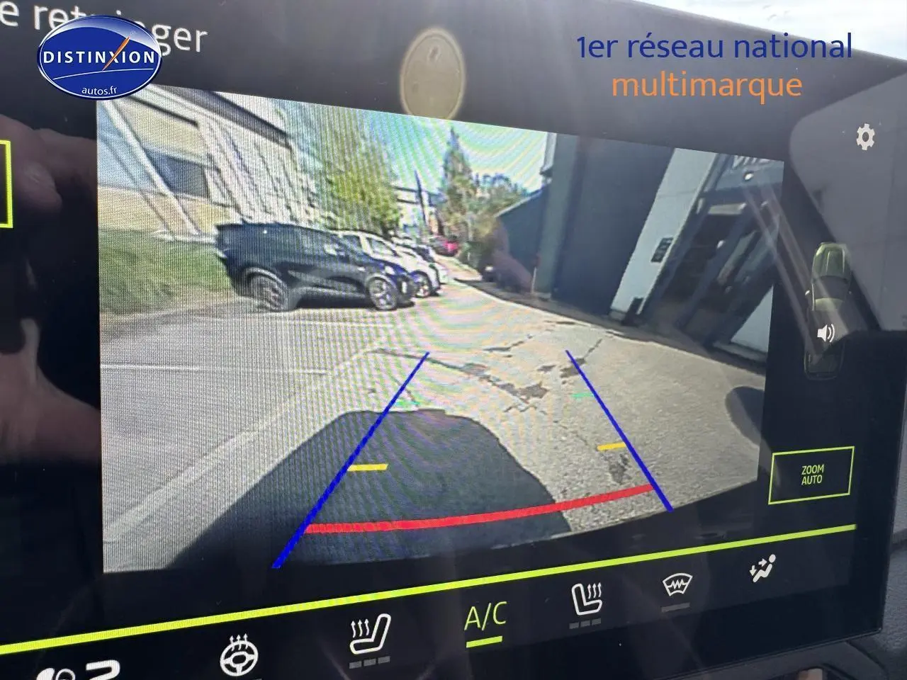 Écran tactile montrant la caméra de recul d'un Dacia Duster vert cèdre, vue arrière avec lignes de guidage colorées.
