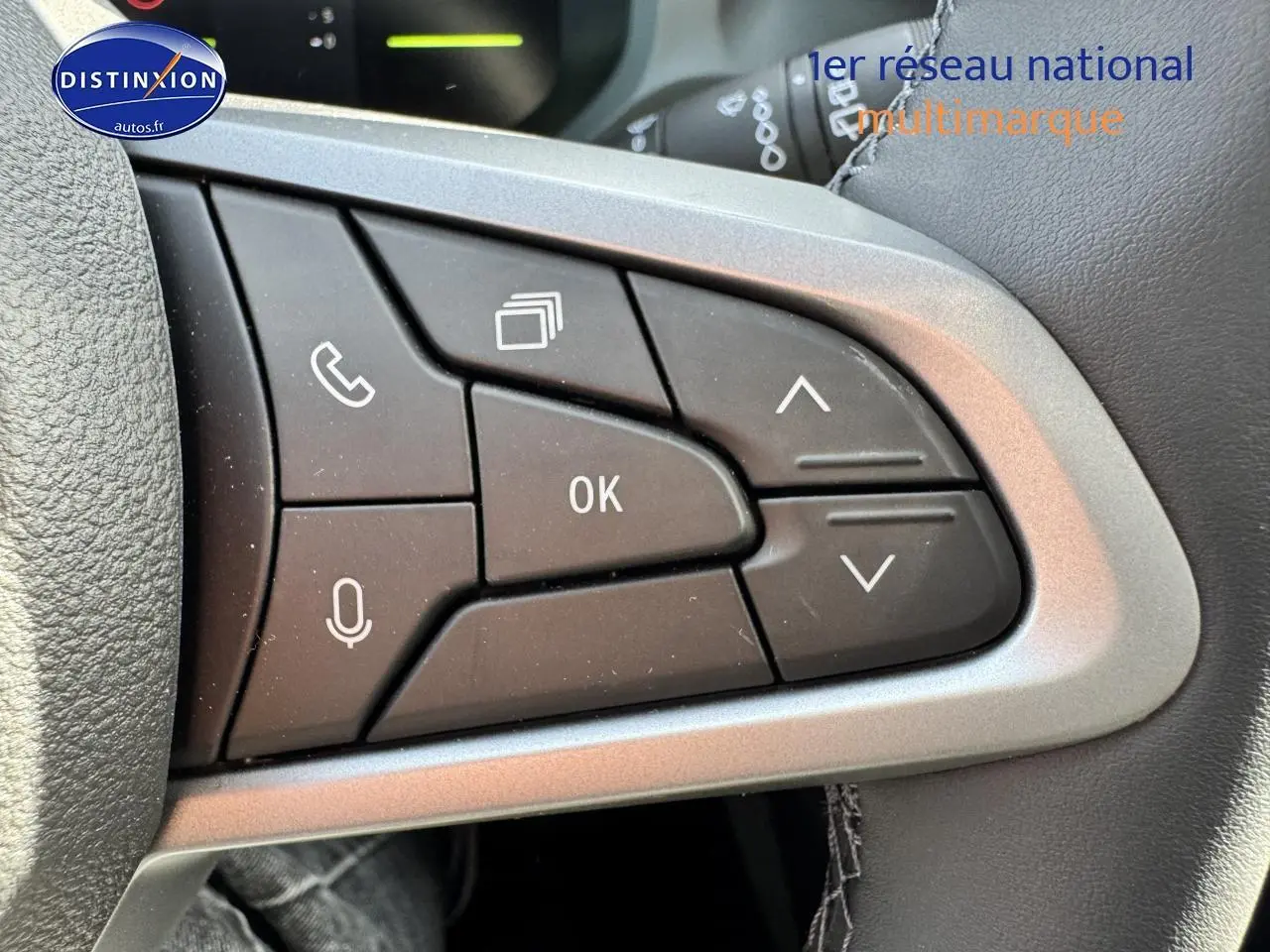 Gros plan sur les commandes multifonctions noires du volant du Dacia Duster 2025, finition Expression, intérieur gris.