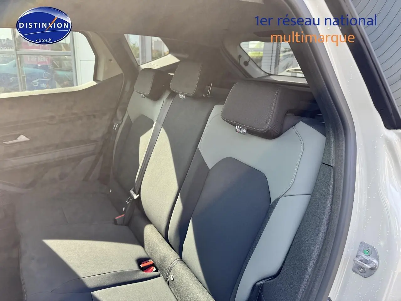 Vue intérieure sur la banquette arrière bicolore gris et noir du Dacia Duster 2025, porte arrière ouverte côté droit.