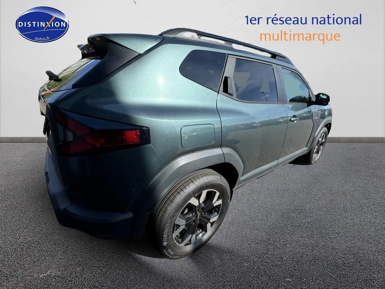 Vue 3/4 arrière droite du Dacia Duster 2025 vert cèdre avec jantes alu et barres de toit visibles.