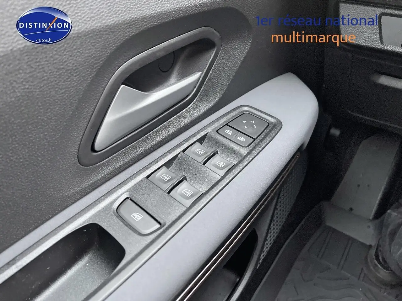 Gros plan sur la commande des vitres électriques côté conducteur du Dacia Jogger blanc, avec poignée de porte grise.
