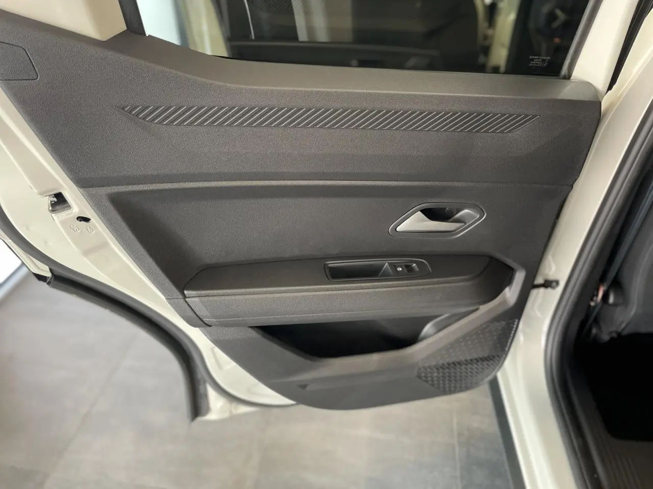 Vue rapprochée de la porte arrière droite beige du Dacia Duster 2025 avec poignée intérieure et commande de vitre.