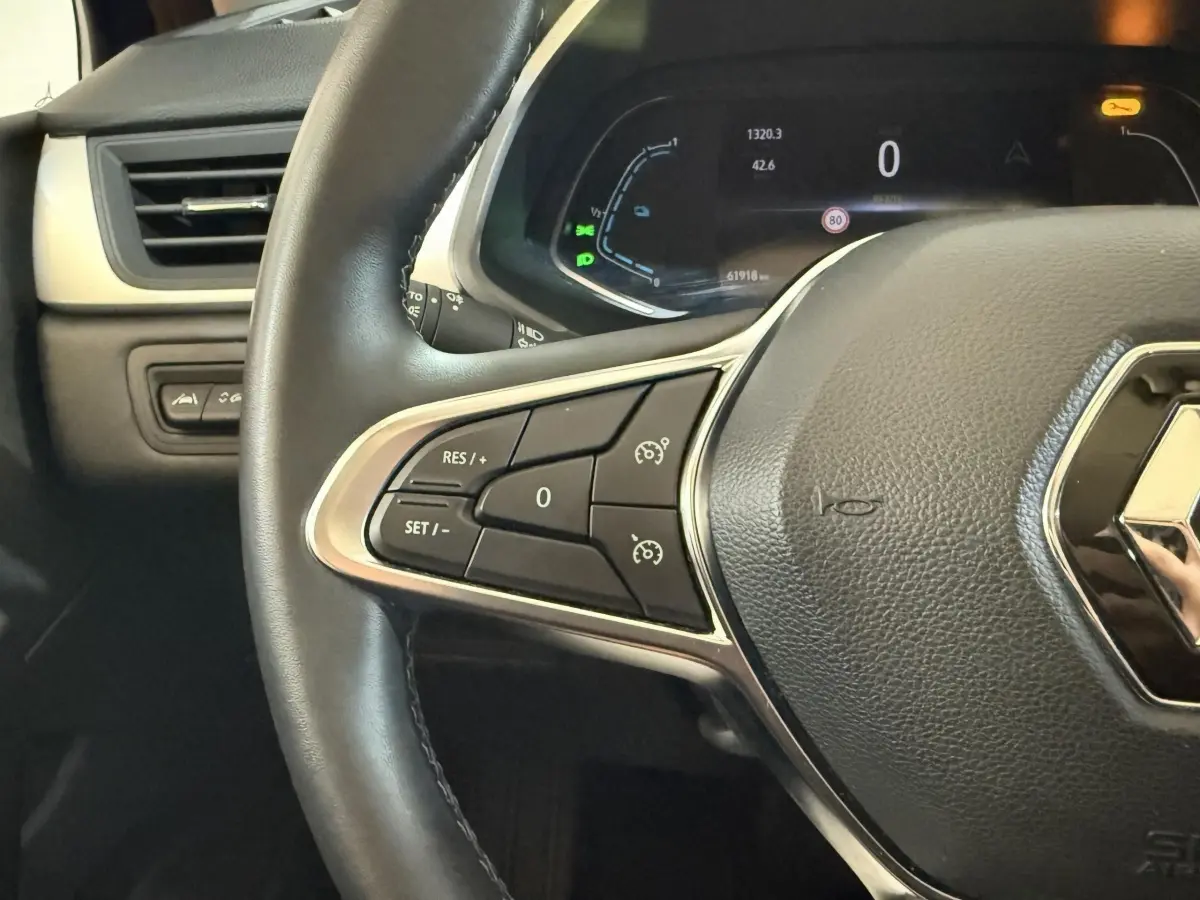 Gros plan sur le volant cuir synthétique noir du Renault Captur 2024 avec commandes multifonctions et tableau de bord numérique.