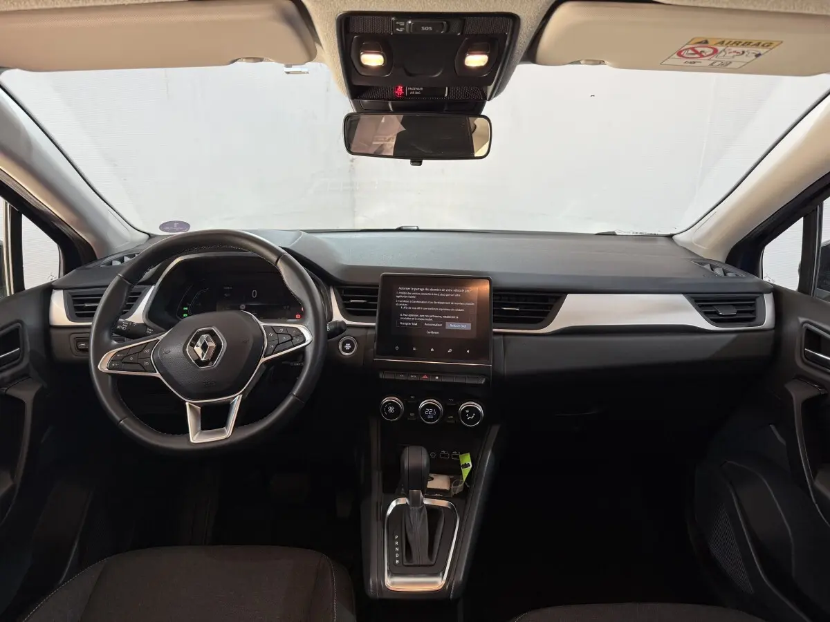 Vue intérieure avant du tableau de bord noir et volant cuir synthétique du Renault Captur bleu 2024 full hybrid.