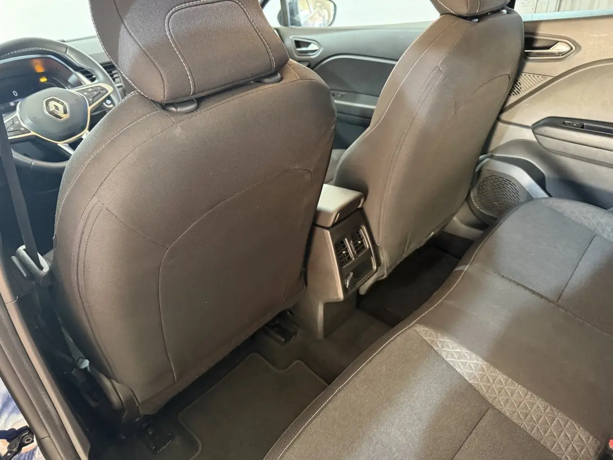 Vue intérieure arrière du Renault Captur 2024, sièges noirs et console centrale avec aérateurs visibles.