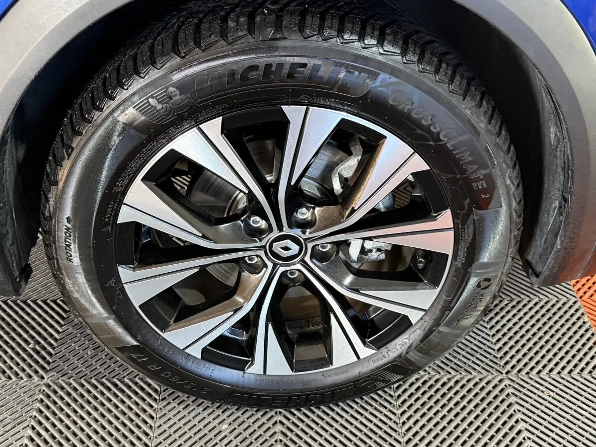 Gros plan sur la roue avant droite du Renault Captur bleu 2024 avec jante alliage bicolore et pneu Michelin.