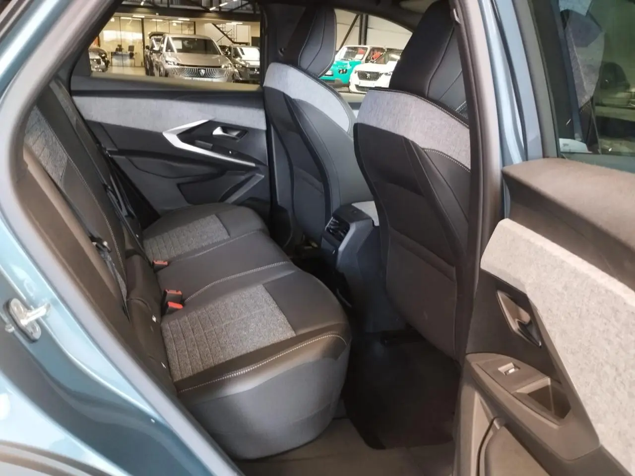 Vue côté gauche arrière de l’habitacle du Peugeot 3008 bleu Azul, sièges tissu gris et noir avec surpiqûres claires.