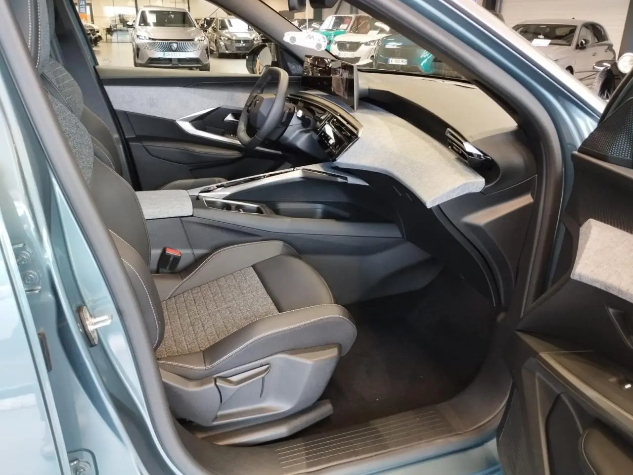 Vue intérieure côté passager avant du Peugeot 3008 Bleu Azul 2025 avec tableau de bord tissu clair et écran incurvé flottant.