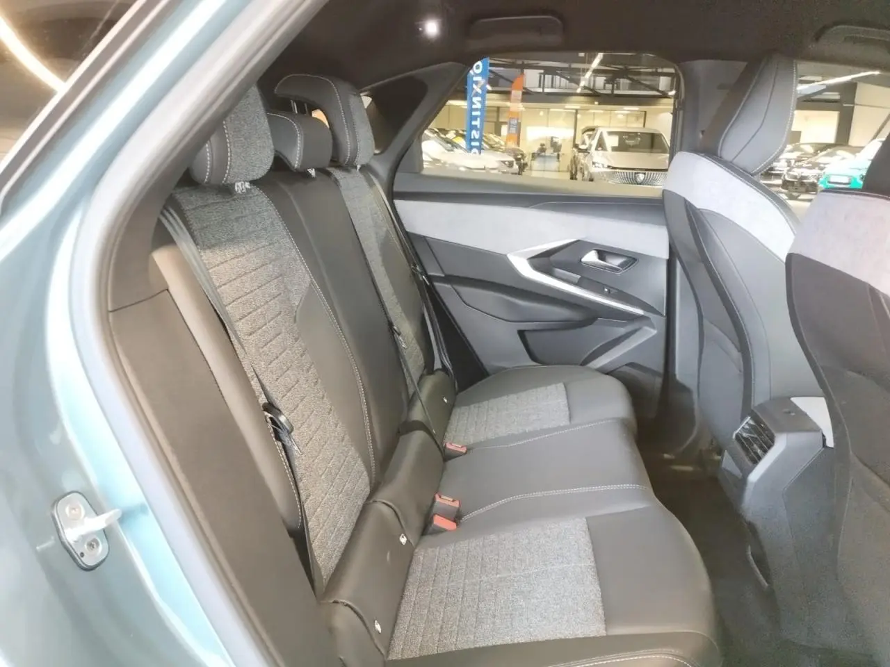 Vue intérieure côté gauche des sièges arrière en tissu gris et cuir noir du Peugeot 3008 Bleu Azul 2025 hybride.
