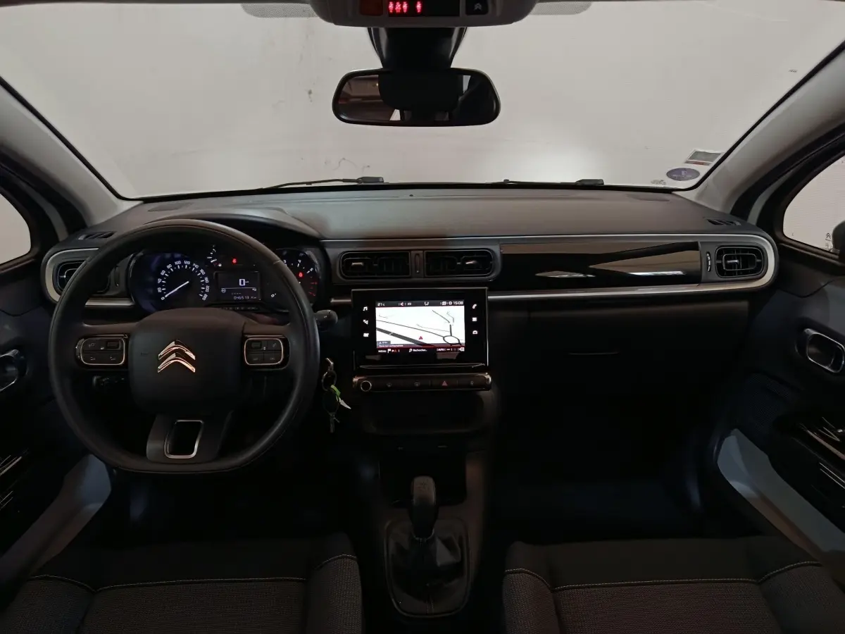 Vue intérieure frontale du tableau de bord noir de la Citroën C3 avec écran tactile de navigation et volant multifonction.