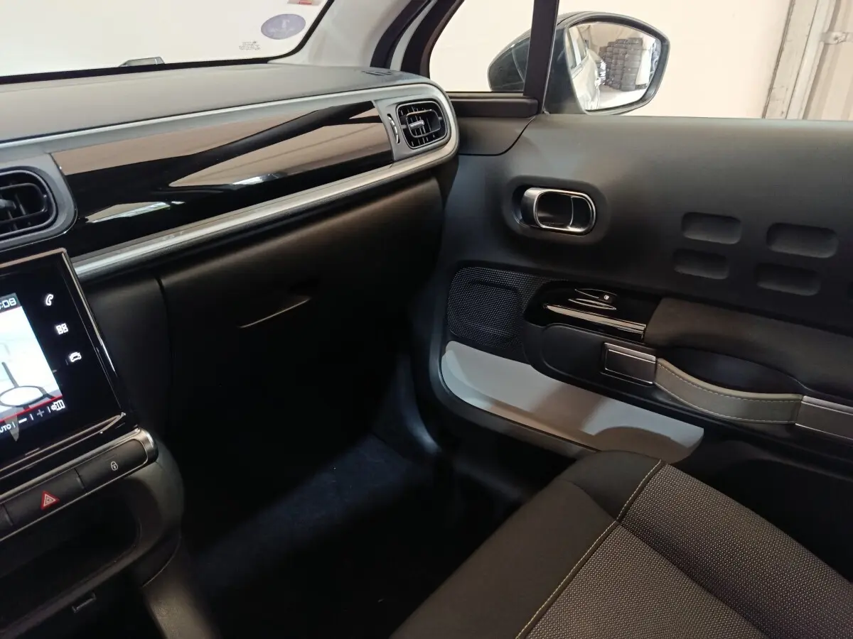 Intérieur côté passager de Citroën C3 2020, tableau de bord noir brillant et porte avec poignée design grise.