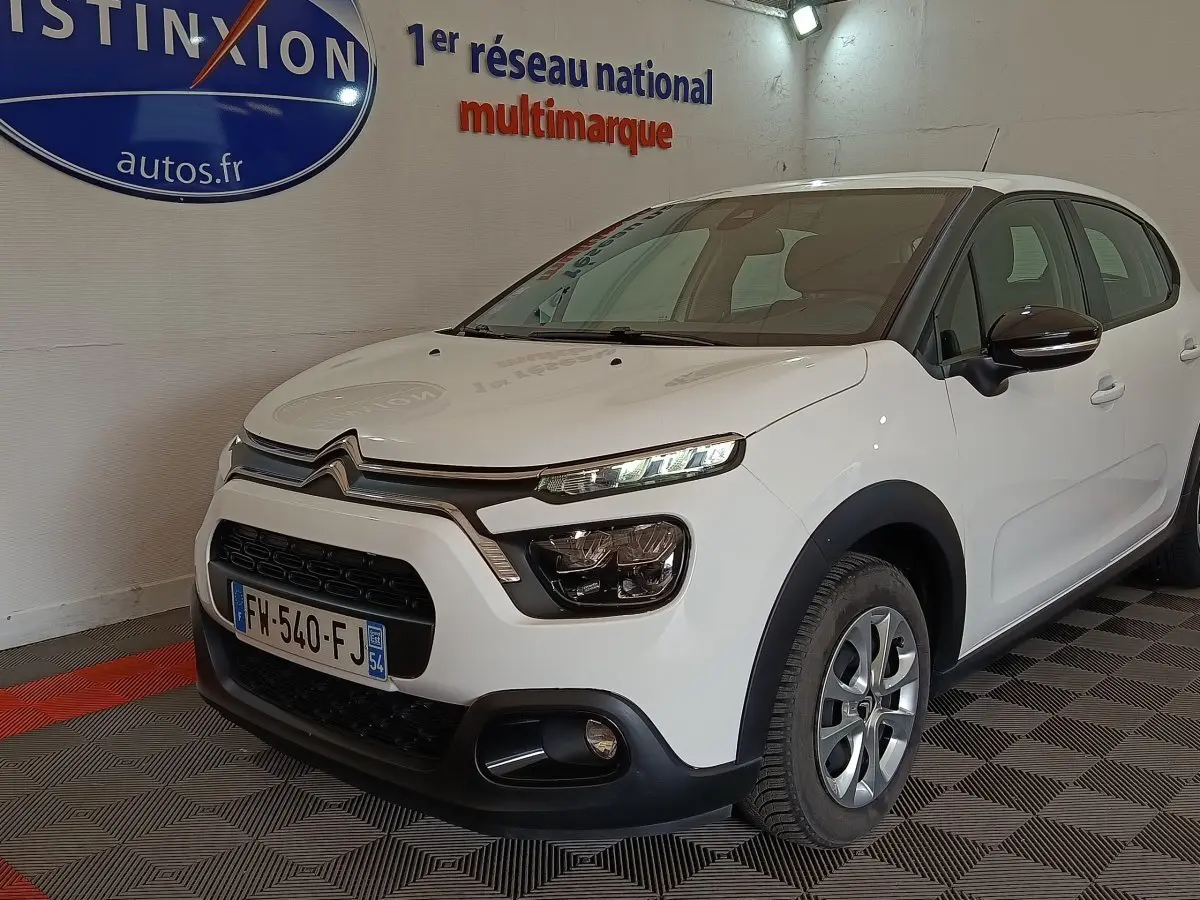 Citroën C3 blanche vue 3/4 avant droit en intérieur, avec phares LED et rétroviseurs noirs ton caisse.