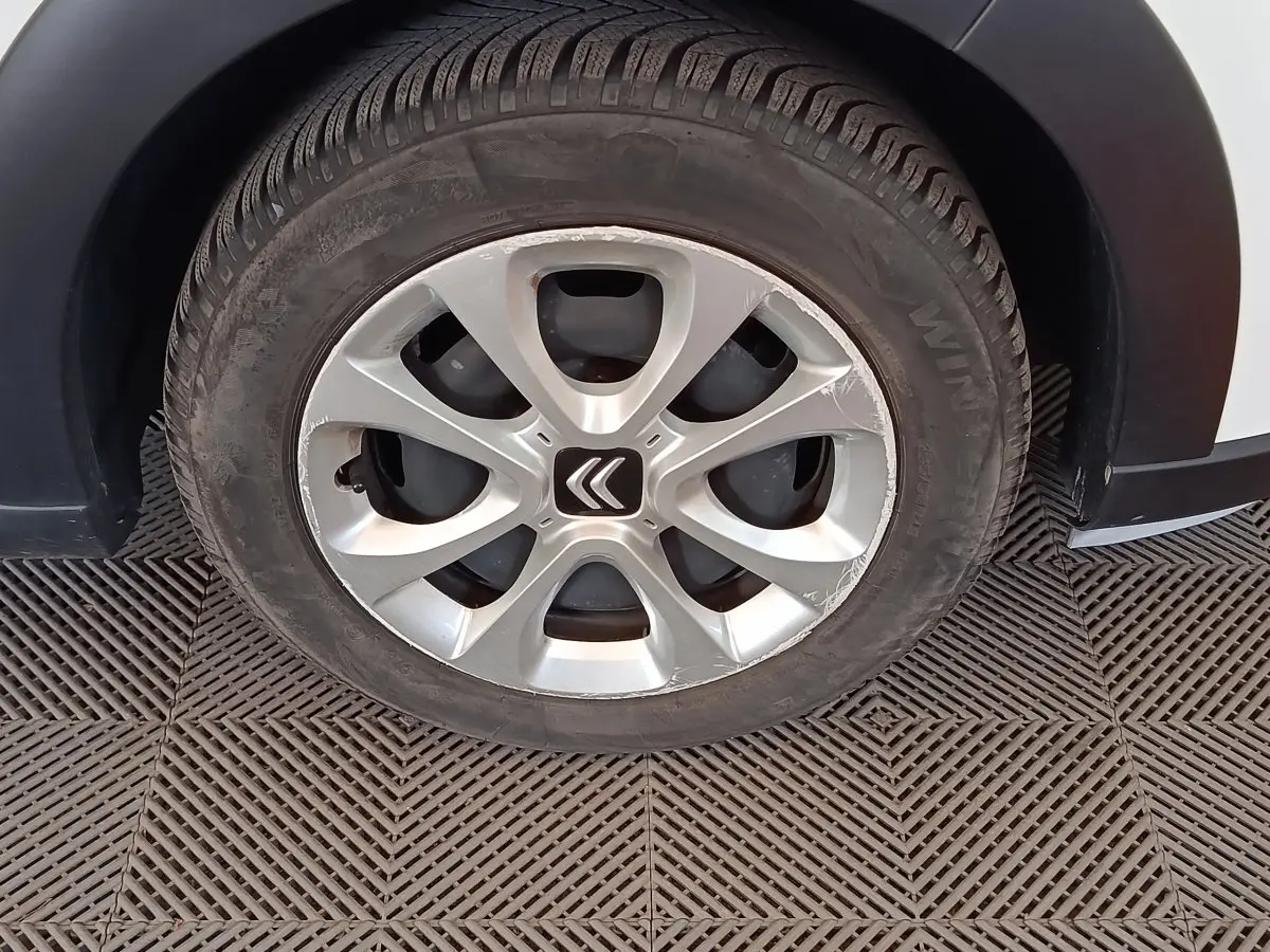 Gros plan sur la roue avant gauche d'une Citroën C3 blanche, avec jante alliage et logo Citroën central.