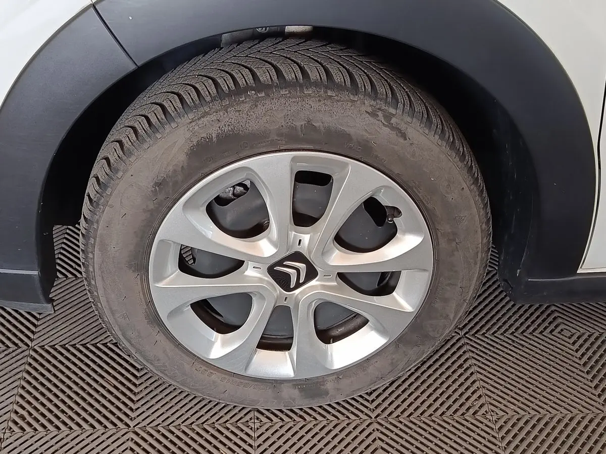 Gros plan sur la roue avant droite d'une Citroën C3 blanche avec jante argentée et logo Citroën au centre.