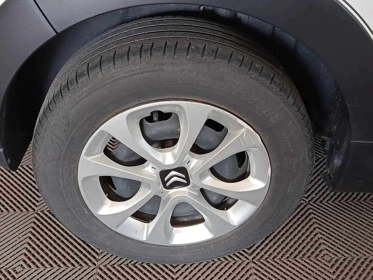 Gros plan sur la roue arrière droite d'une Citroën C3 blanche, avec jante alliage et garde-boue noir.